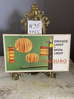 Photo showing the front of the cardboard box with images of the lamp prototypes and product branding.