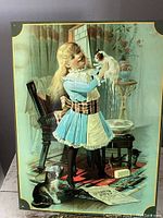 Full view of the reproduction tin advertising sign showing the girl holding a white cat with a black and white cat on the floor.