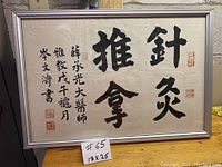 Front view of the framed Asian calligraphy artwork with visible signatures and red seal stamps.