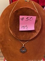 Full view of the gold plated chain and red stone pendant on display bust showing the length of the chain and style of pendant.