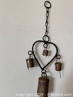 Complete view of the vintage heart-shaped iron wind chime with four copper bells hanging from iron rings attached to the frame, showing full item from hanger to bells.