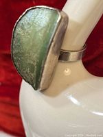 Close-up front view of vintage sterling silver ring with large green stone showing texture and color of stone and ring band.