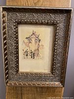 Full front view of framed vintage artwork showing detailed metal frame and central signed drawing.