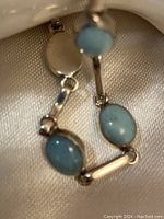 Close-up of turquoise oval stones and sterling silver link detail in bracelet chain.
