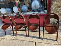 Four vintage Thonet style bentwood folding chairs shown side by side on a sidewalk outside a store under natural light, highlighting their curved backrests and rounded seats.