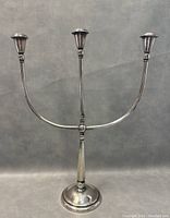 Front view of the three-arm silver plated candleholder showing overall shape, dimensions, and condition.