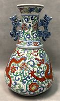 Front and side view of the porcelain vase showing the colorful dragon motif and floral decorations with blue dragon-shaped handles on the neck.
