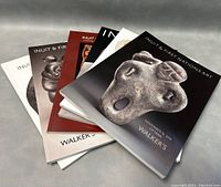 Photo showing six art books stacked and fanned out, focusing on Inuit and First Nations sculptures on covers, with different colored bindings and detailed stone sculpture photographs.
