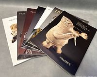 Seven Inuit & First Nations art books stacked and fanned out showing cover sculptures and titles