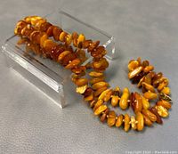 Full view of natural amber necklace laid in looped shape with beads in various warm tones.