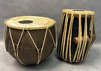 Pair of Indian tabla drums on gray background showing front and side angles for identification.