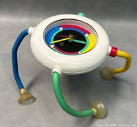 Post modern desk clock resting on surface showing side and legs with suction cups