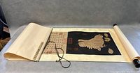 Photo showing the unrolled scroll partially extended showing hen and chicks print with calligraphy and scroll edges