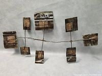 Metal wall art sculpture laid flat showing signed panels and abstract geometric design.