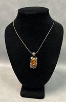 Front view of pendant on chain displayed on black necklace stand