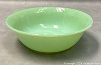 Side view of the green jadeite bowl showing smooth curved shape and glossy finish.