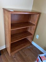 Front view of maple bookcase showing three shelves with visible scratches.