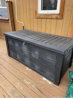 Front perspective of black storage box on deck showing overall condition and size