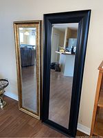 Both mirrors side by side showing scale and style differences, one black framed, one gold framed.