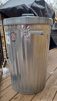 Front view of tall aluminum garbage can with handle, placed on deck.