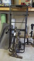 Front view of the cargo carrier rack and bike rack leaning against a workbench with visible hitch attachments and wheels