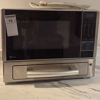 Front view of LG microwave oven with oven drawer closed, showing stainless steel handle and black glass front.