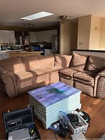 Front view of brown curved reclining sectional sofa in living room with coffee table and kitchen in background