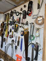Wide angle view showing tools organized on pegboard including saws, clamps, levels, rulers, staplers, and pouches of miscellaneous small items.