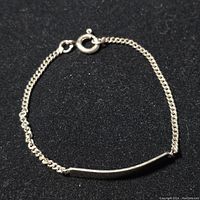 Front view of the sterling silver bracelet showing the curved side of the rectangular bar and chain clasp.