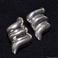 Pair of sterling silver clip-on earrings shown from an angled front perspective on a black background.