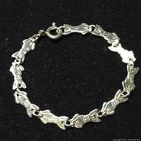 Silver bracelet on a black background showing front view of linked bunny-shaped links and spring ring clasp.