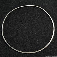 Top-down view of entire thin silver bangle showing circular shape and smooth clean surface.