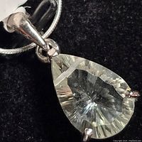 Close-up of the green amethyst pendant showing the pear shape and sterling silver prongs with chain attached.