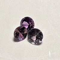 Three round faceted color change sapphires, assorted views showing color variation