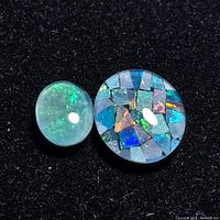 Two opal stones on black background, one translucent green flash cabochon and one multicolor mosaic cabochon.