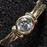 Close-up photo showing the sterling silver band and clear round cubic zirconia stone in bezel setting, highlighting band texture and stone facets.