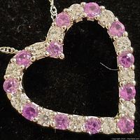 Close-up of heart-shaped pendant showing alternating pink and clear round gemstones set in sterling silver.