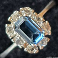 Close-up photo showing the rectangular blue gemstone surrounded by clear stones on sterling silver ring.