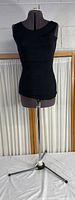 Full view of the female clothing form dressed in a black sleeveless top on an adjustable metal tripod stand.