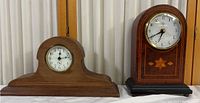 Shows two mantel clocks: left is Ansonia clock with arched wooden case, right is Elgin clock with rectangular dark wooden case and marquetry