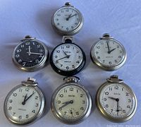 Top-down view showing all seven Bull's Eye pocket watches with various dial colors and designs.
