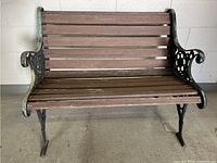 Front view of the garden bench showing wooden slat seat and back with cast iron decorative sides