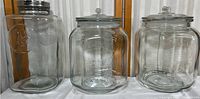 Three large glass containers displayed side by side on a white surface, showing their relative shape and size.