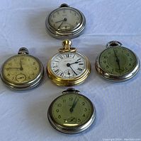 Five Westclox pocket watches arranged on flat surface showing face details and overall condition