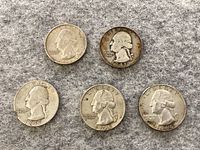 Five silver quarters arranged on a gray felt background showing dates 1935, 1941, 1947, 1959, and 1964.
