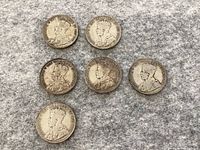 Six Newfoundland 50 cent coins featuring King George V arranged on a grey surface.