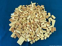 Top-down view of a pile of yellow LEGO bricks and pieces on a blue fabric surface.