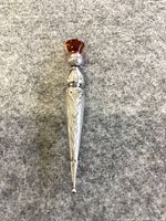 Front view of the sterling silver kilt or lapel pin with amber-colored stone on gray fabric background.