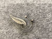 Top view of the sterling silver leaf pin brooch showing polished leaf shape and wire loops ending in balls.
