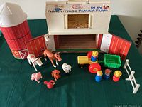 Full view of the playset including barn, silo, tractor, cart, people, animals, and fence on green surface